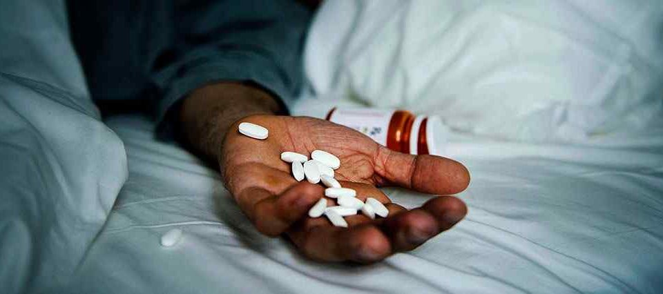 hand with pills on bed